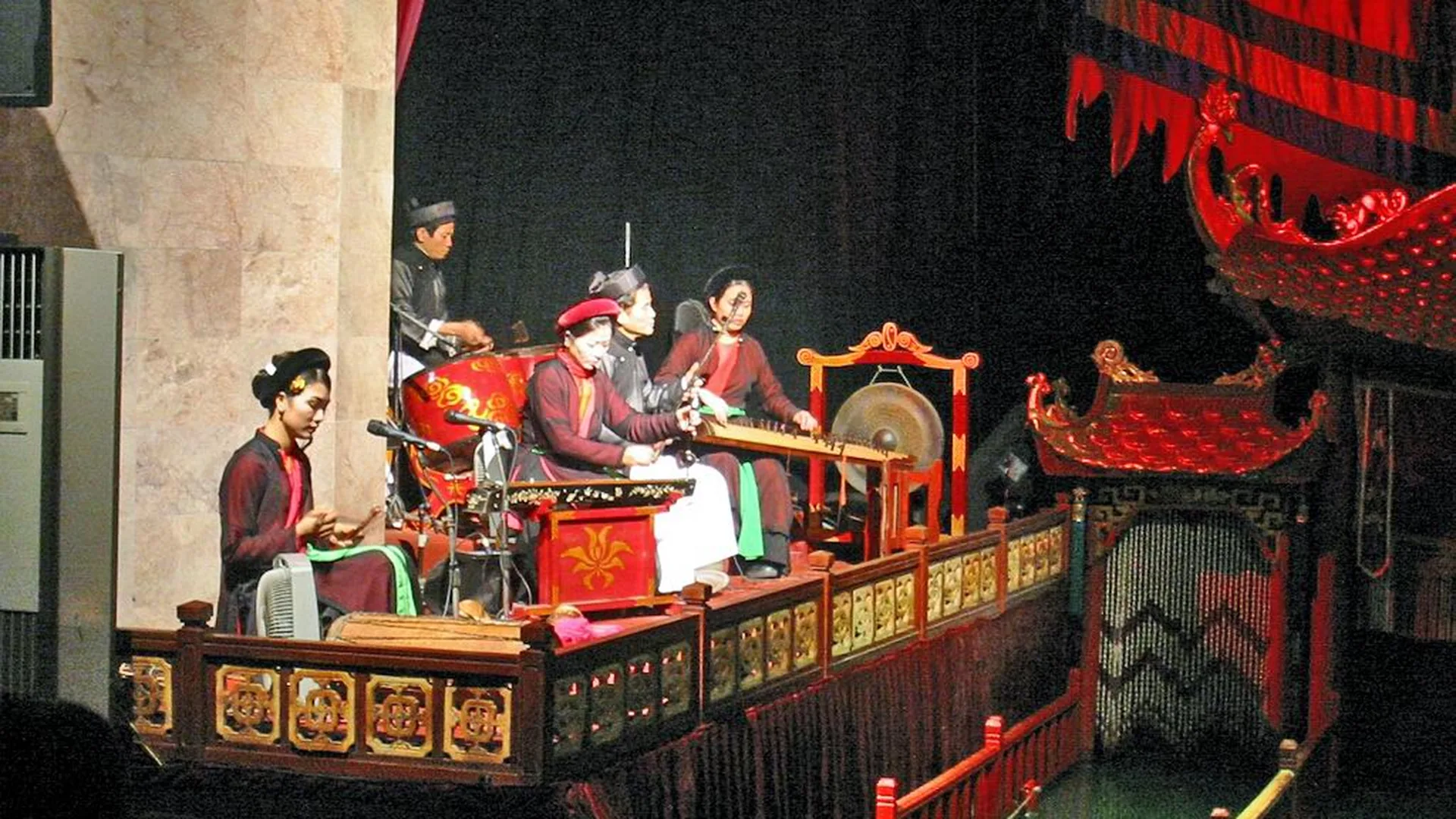 Traditional Vietnamese water puppets in bright lacquered colours performing on a water stage with a temple-style backdrop